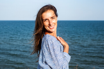 Smiling young woman in dress on the background of the sea.