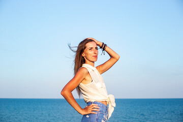 Beautiful young woman in denim shorts and shirt at the sea.