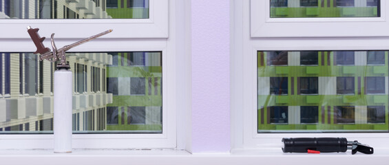 a balloon with mounting foam stands on the windowsill before repairing cracks, insulation, a gun with silicone, close-up