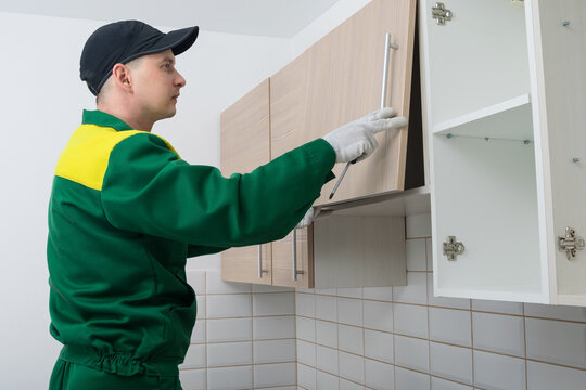 the master of furniture assembly, checks the correct installation of the door on the hanging cabinet