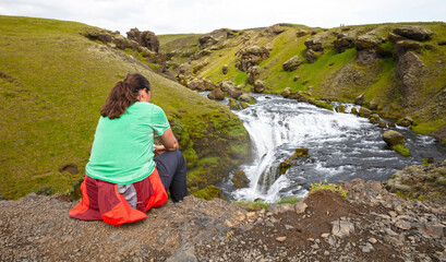 Naklejka na ściany i meble Woman watching the Skoga river before the Skogafoss waterfall