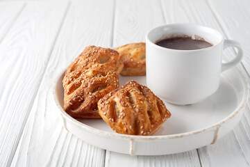 Mug with hot chocolate and sweet puffs on a wooden table