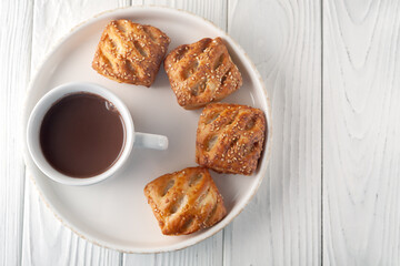 Mug with hot chocolate and sweet puffs on a wooden table