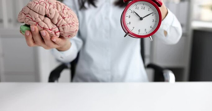 Woman stretches forward a mock up of human brain and alarm clock