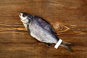 One whole salted sun-dried bream with label on tail on wooden background