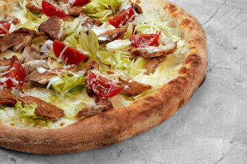 Delicious pizza Caesar style with white sauce, chicken, parmesan, egg, cherry tomatoes and fresh lettuce at wooden background. Restaurant pizzeria menu with delicious taste pizza Caesar.