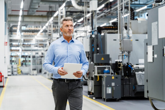 Businessman with tablet PC inspecting automated industry