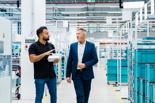 Businessman explaining engineer over electrical equipment at factory