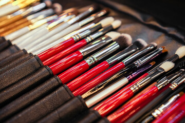 Set of makeup stylist brushes. Different makeup brushes in black leather case. Close up. Selective focus