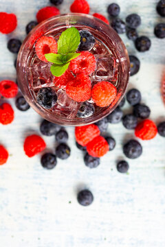 Glass of gin tonic with mint, ice cubes and raw berries