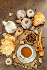 Breakfast concept with a cup of coffee, croissants, milk jug, and decorative crochet pumpkins