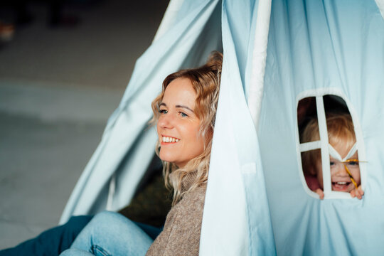 Mother sitting with girl and man in tent at home