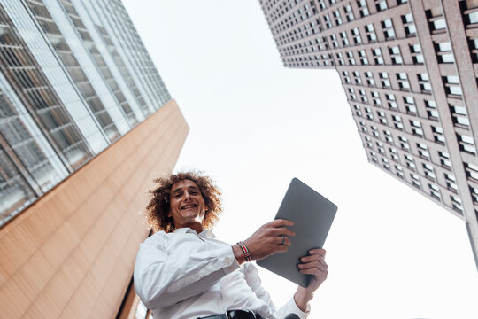 Smiling businessman holding tablet PC in city