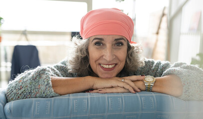 Smiling senior woman with bandana relaxing on sofa at home