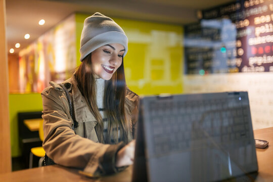 Smiling woman using laptop in cafe