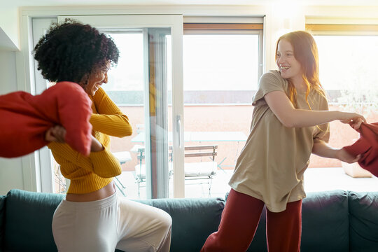 biracial girlfriends fighting with pillows in the living room