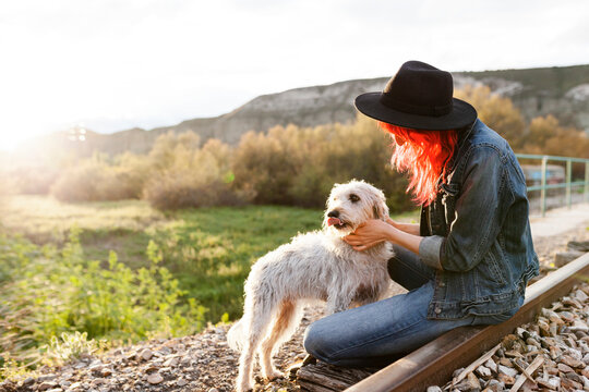 Woman stroking Border Collie dog sitting on railroad track