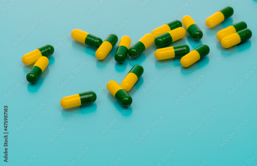 Canvas Prints Green-yellow capsules spread on blue background. Tramadol capsule pills for relieve severe cancer pain. Painkiller medicine. Opioids drug. Pharmaceutical product for pain treatment. Prescription drug.