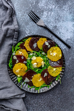 Studio shot of plate of vegetarian salad with orange and beetroot slices, arugula, Parmesan and black sesame seeds