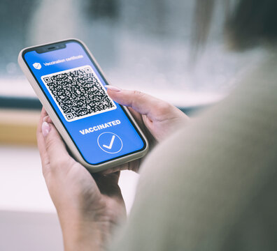 Woman with COVID-19 vaccination certificate OR code on mobile phone screen