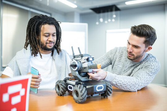 Technicians working with remote controlled robotic combat tank at workshop
