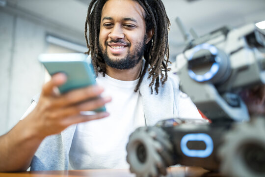 Engineer operating robotic combat tank through remote control at workshop