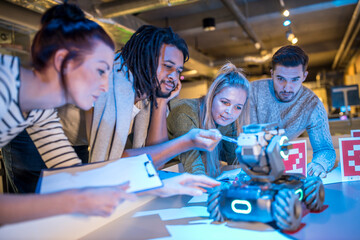 Technicians discussing with each other looking at robotic combat tank in workshop