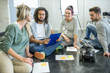 Engineers and technicians discussing with each other sitting at robotic workshop