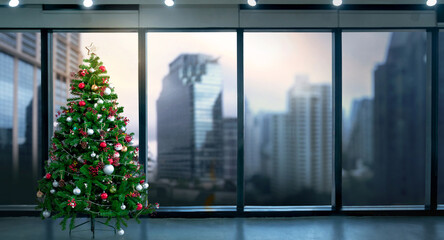 Christmas tree in modern office near big window and building view in city