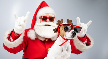 Santa claus and santa's helper in sunglasses on a white background. Jack russell terrier dog in a deer costume