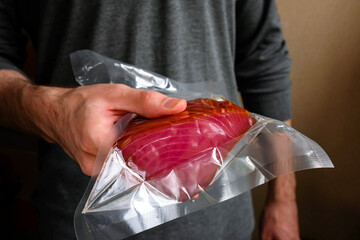 Tuna in the package. A man holding a packed red fish in his hand