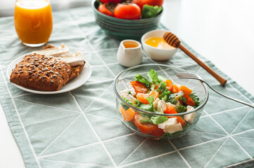 Vegan breakfast or lunch. Light sweet and sour salad with persimmon, tangerines and cheese. Winter vitamin salad on white table with a green napkin Diet food. Selective focus 