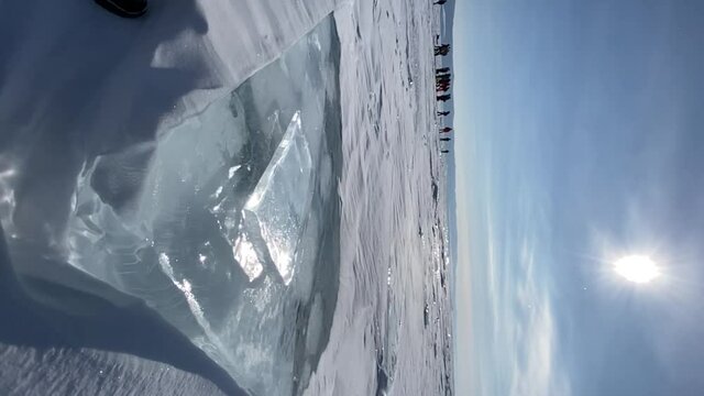 A crystal clear piece of ice crushes against a block on the frozen Lake Baikal and crumbles into small fragments. Vertical view. Slow motion