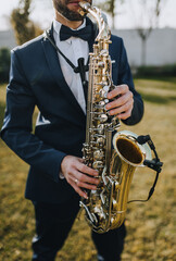 Fototapeta premium Stylish man in suit, musician, professional saxophonist in suit plays the saxophone.