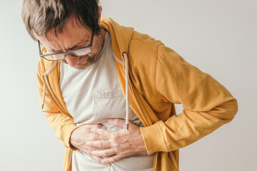Aching stomach pain, man pressing the lower abdomen of his body with painful grimace