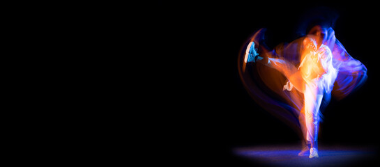 One sportive girl, hip-hop dancer practicing alone at stage on dark background in purple neon mixed...