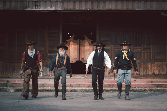 Vintage style cowboys group wearing cowboy shirts and trousers everybody showing gun in hand ,like group of bank robber.