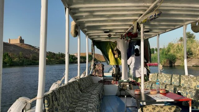 Felluca ride on the Nile River, overlooking the desert and historic buildings on the banks of the river. Felluca ride