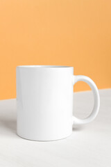 White ceramic cup with copy space front view. Drink mug with empty space, mockup, template for design and logo close-up on colored background.