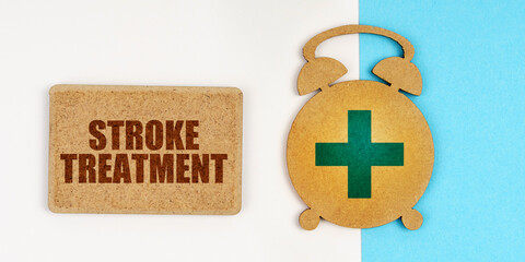 On the white and blue surface are an alarm clock and a sign with the inscription - stroke treatment