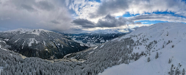 Fototapeta na wymiar ski resort on a snow covered mountains, cloudy sky with sun rays, Christmas atmosphere. 