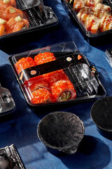 Set of sushi rolls packed in closed plastic containers for delivery to client