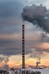 Dark smoke and steam from chimney in factory against the sky