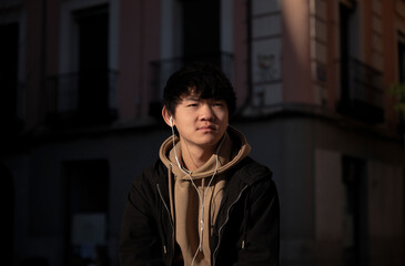 Asian teenage boy with earphones on street. Madrid. Spain