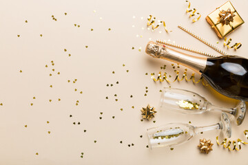 Bottle of champagne with colored glitter, confetti and gift box space for text on colorfull background, top view. Hilarious, christmas and birthday celebration © sosiukin