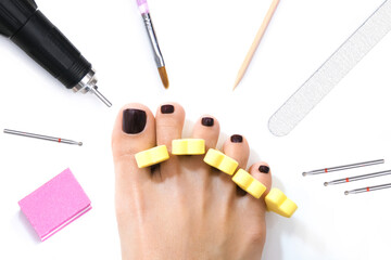 beautiful female feet with shellac coating on the nails, on a white isolated background. finger separator
