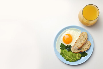 Plate of breakfast and glass of juice on white background