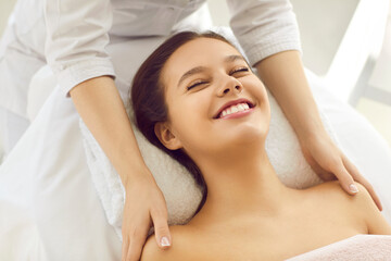 Happy woman smiling while getting a facial at spa salon. Cosmetologist providing effective professional cosmetic facial treatment for clear smooth fresh perfect healthy skin. Close up. Beauty concept