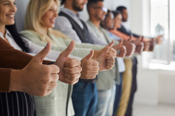 Row of happy successful young modern business people giving thumbs up. Team of many confident...