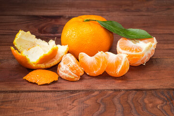 One whole and peeled tangerines on the old rustic table